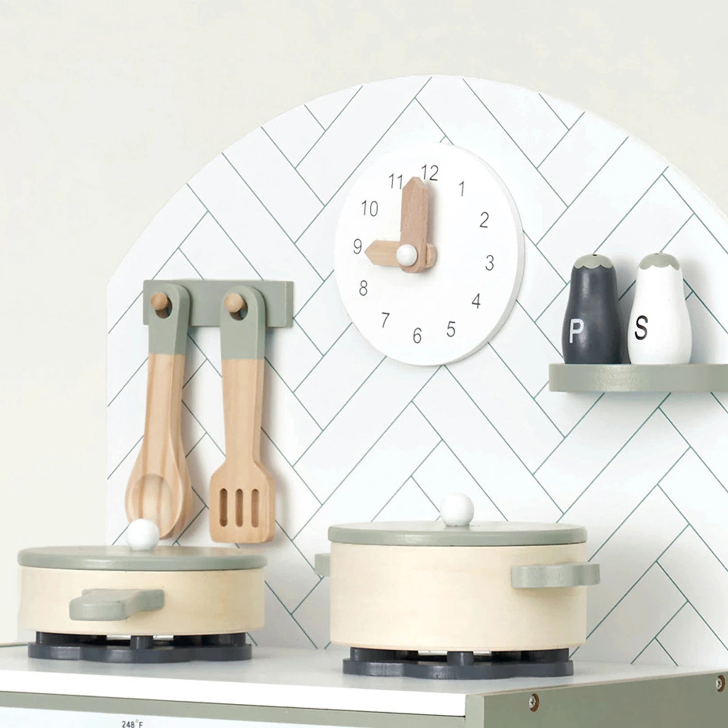 Mint kitchen playset with pots, pans, and utensils on a white surface against a white wall with a play clock.