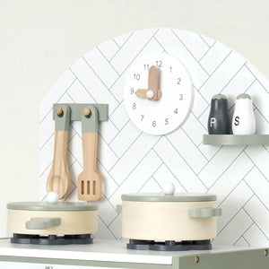 Mint kitchen playset with pots, pans, and utensils on a white surface against a white wall with a play clock.