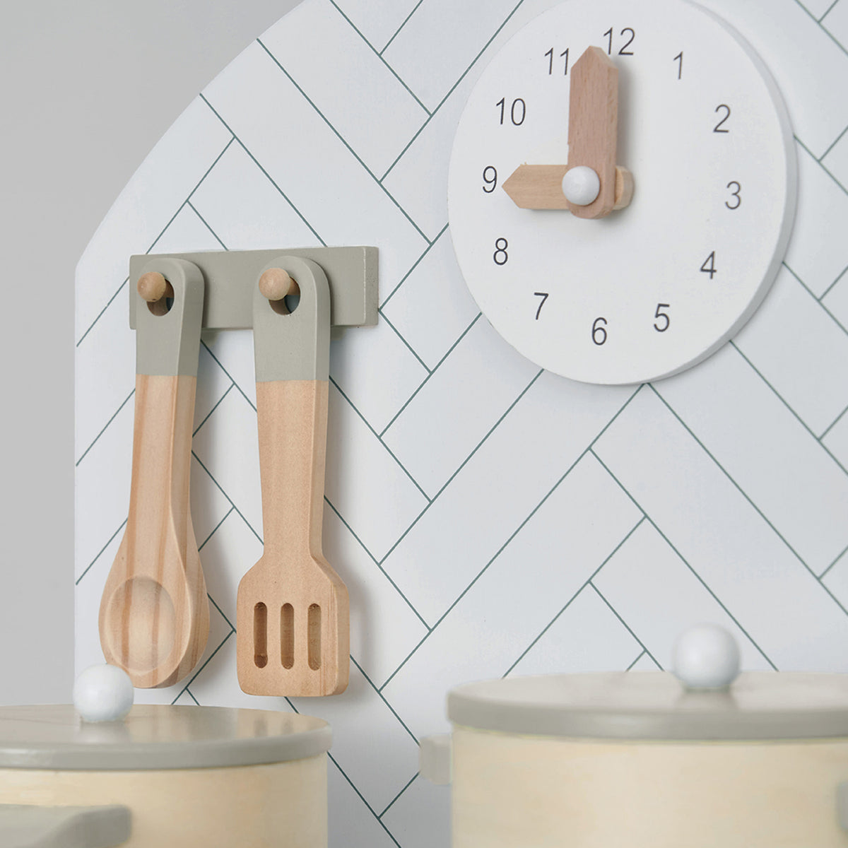 Close view of analogue clock and utensils of wooden play kitchen.