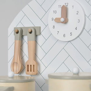 Close view of analogue clock and utensils of wooden play kitchen.