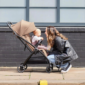 A mother is playing outside with her baby in an Ickle Bubba autofold stroller.