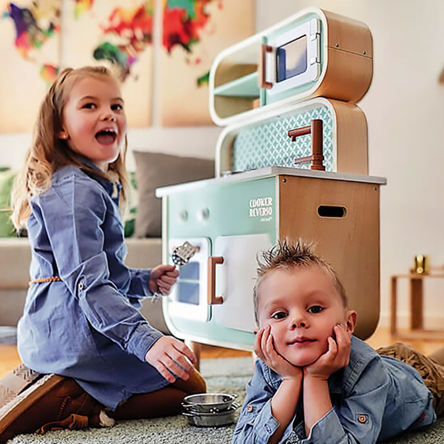 Two kids are playing with the janod reverso play kitchen.