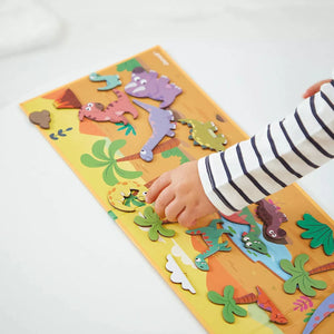 Child arranging magnetic dinosaurs on a prehistoric landscape Magnéti'book Stories set.