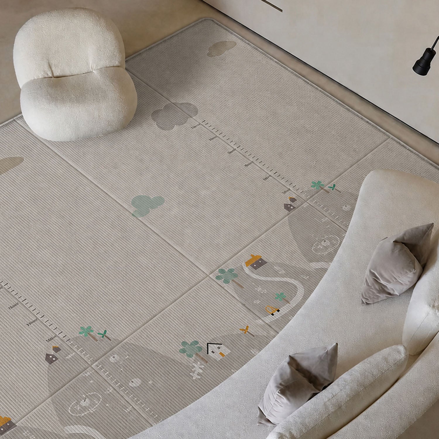 A large play rug with a playful outdoor trail design, shown in a styled living room setting with a curved sofa, a small chair, and a lamp.