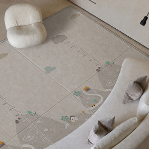 A large play rug with a playful outdoor trail design, shown in a styled living room setting with a curved sofa, a small chair, and a lamp.