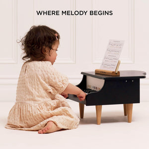 A toddler is playing the wooden grand piano toy.