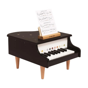 Black toy piano with a music sheet on a white background