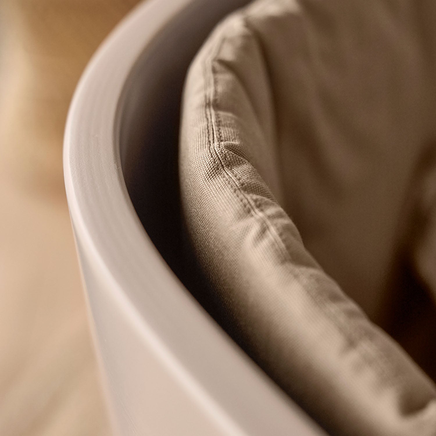 Side view of oval crib with smooth molded wood frame.