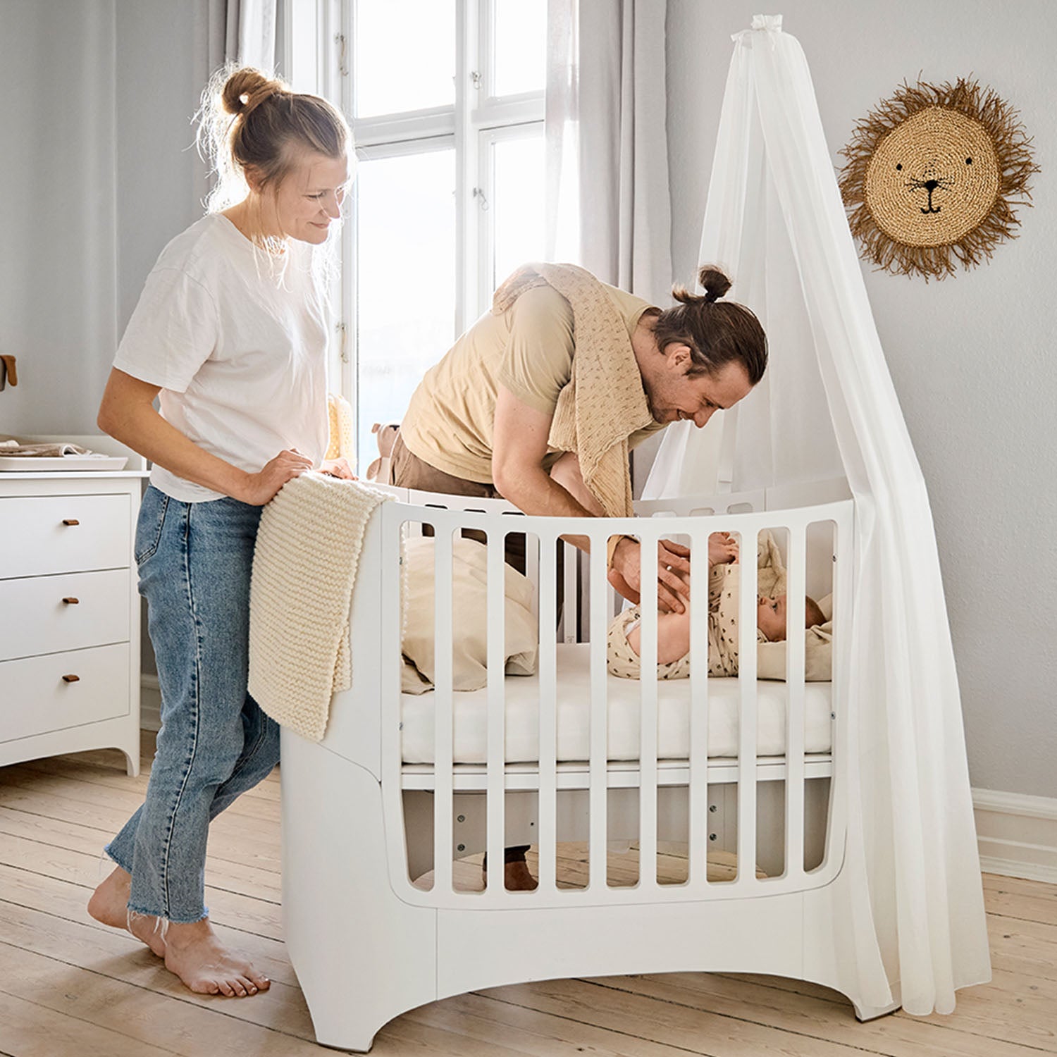 Parent leaning over Leander cot to comfort baby.