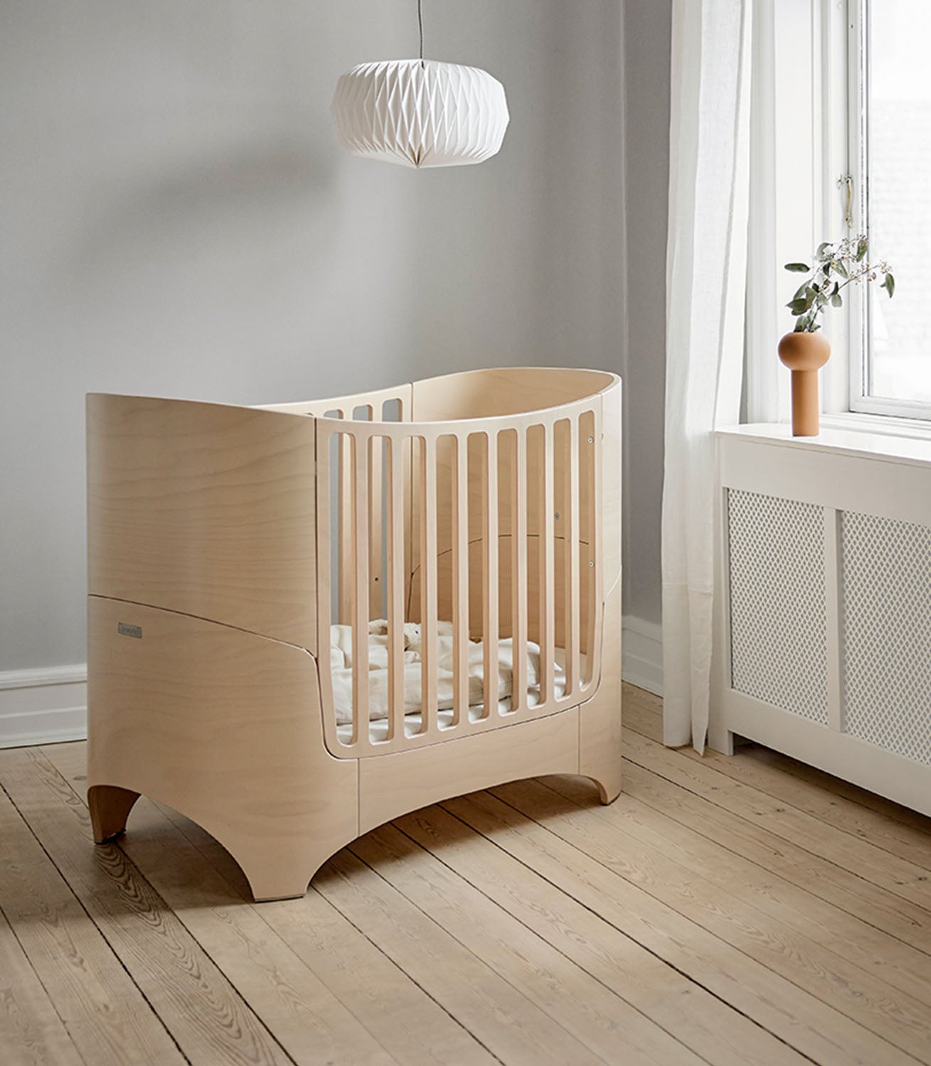 Scandinavian baby bedroom with natural wood oval crib.