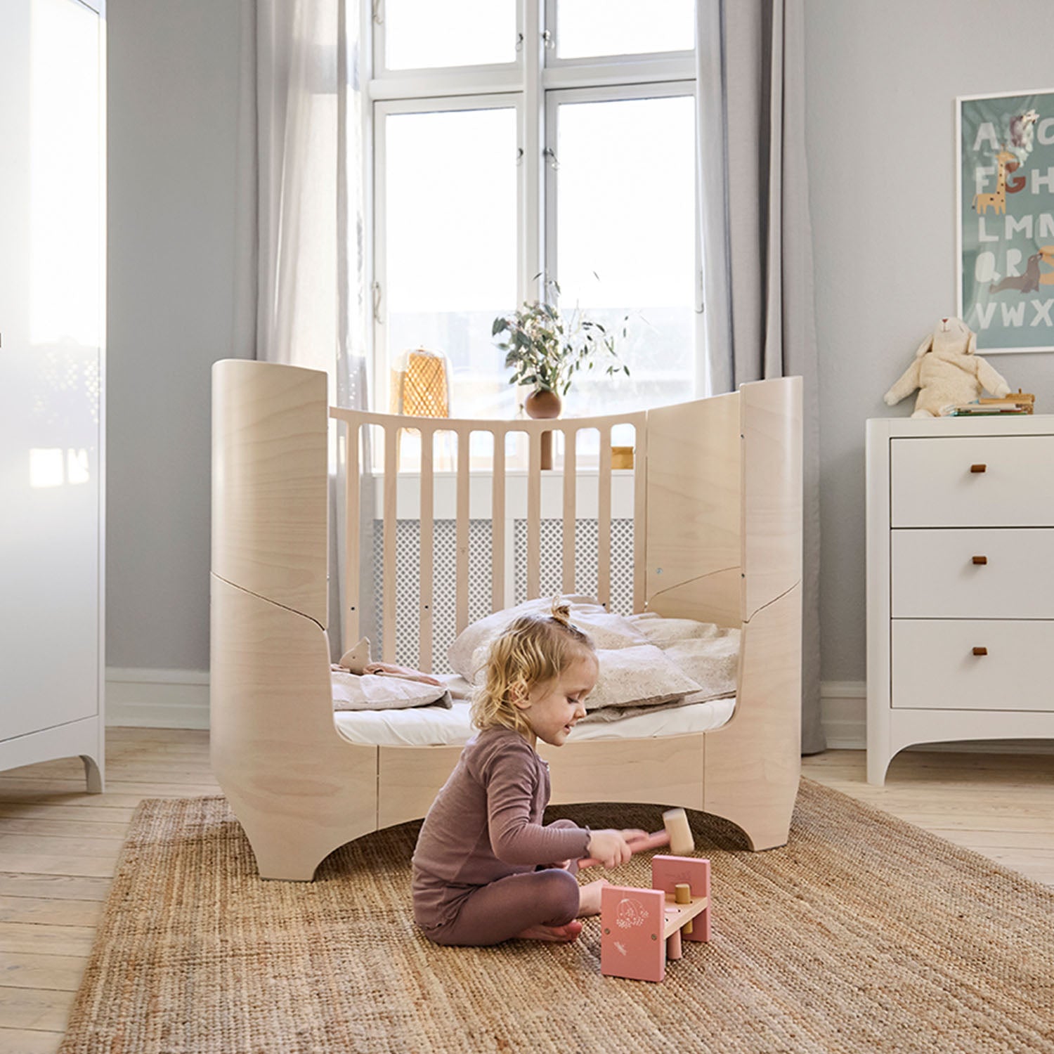 A toddler is playing near leandre baby cot.