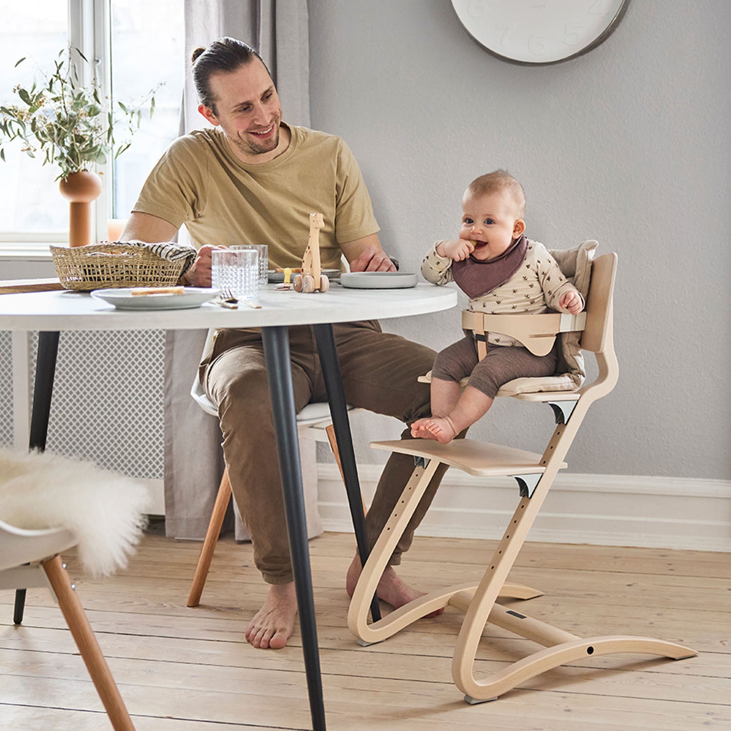 Infant using the Leander highchair with the safety bar and cushion.