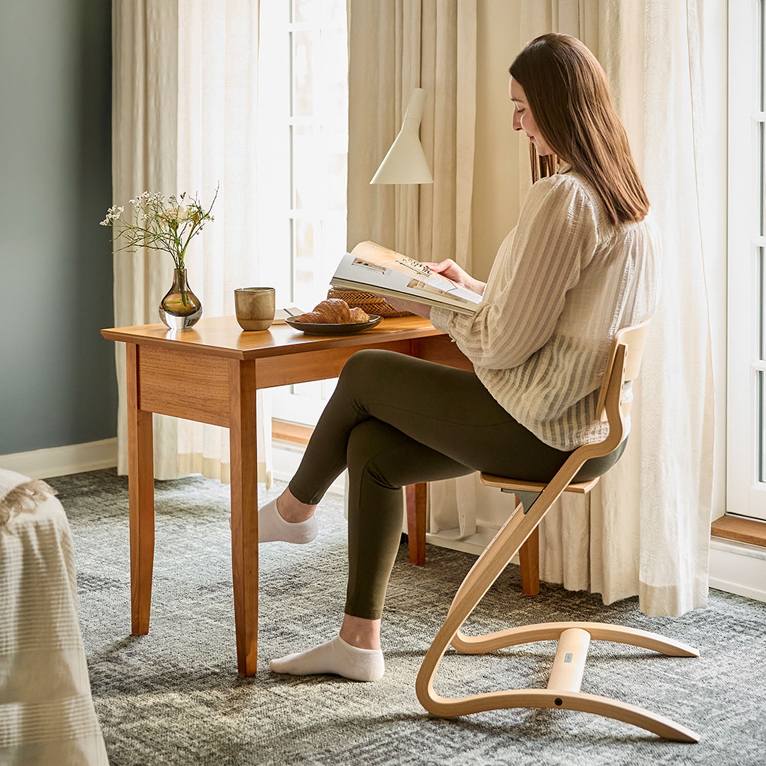 The final configuration of the Leander Louie chair used as a stylish, minimalist dining chair for an adult, highlighting its 100kg+ weight capacity and timeless Nordic look.