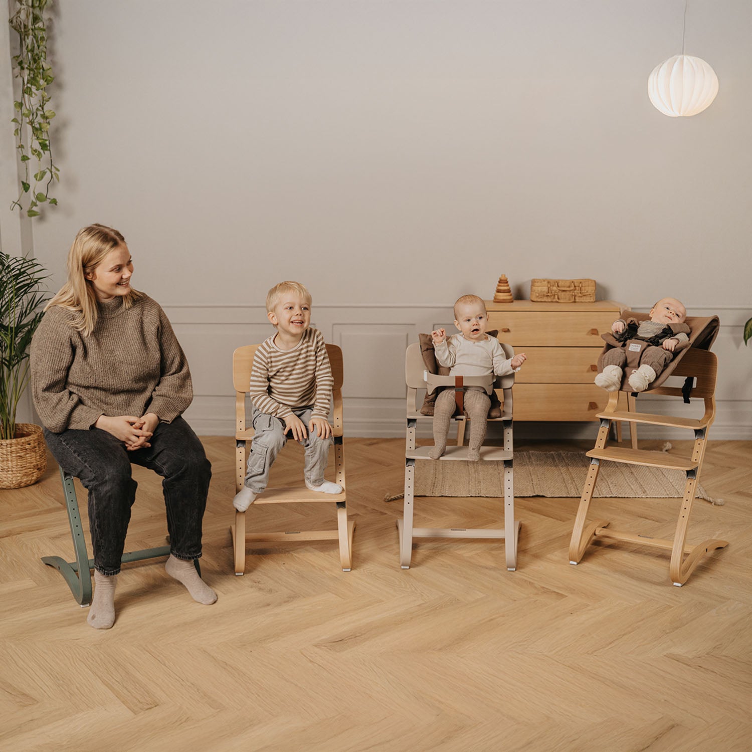High chairs can be used in many different ways from babyhood through adulthood. In this scene, the mother and children are each using the high chair differently, highlighting its versatility across ages and everyday activities.