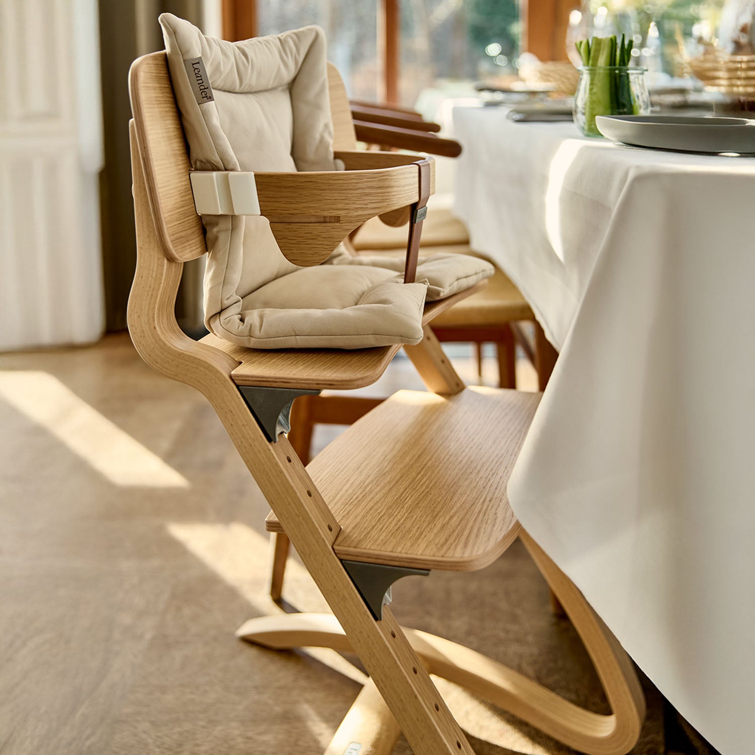 Leander highchair with cushion and safety bar for baby.