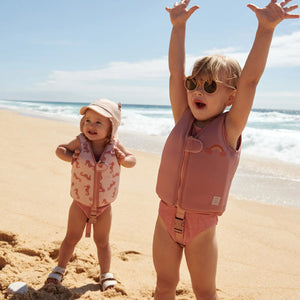 Toddler wearing the liewood swim vest and having fun on the beach.