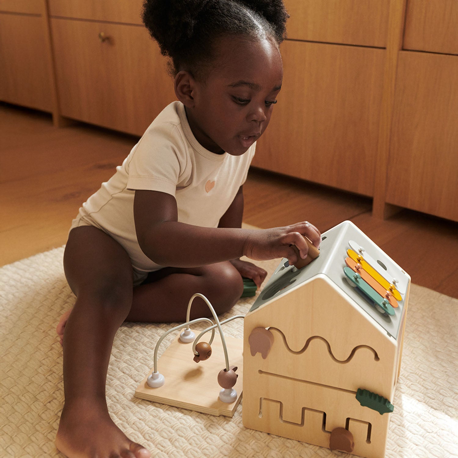 Montessori-style wooden activity cube for fine motor skills.