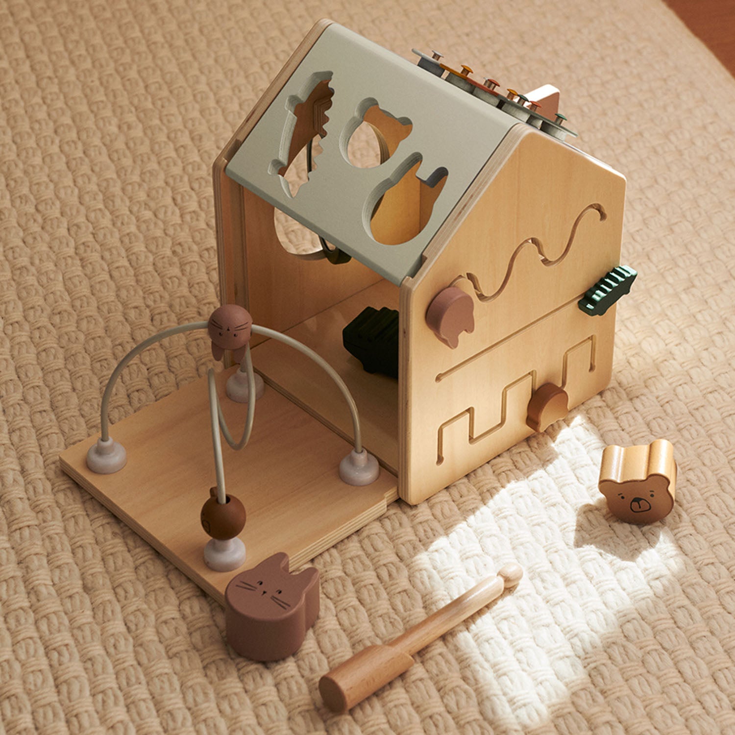 House-shaped wooden activity toy in Tuscany Rose colours.