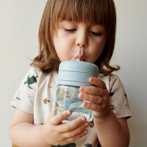 A toddler is drinking water with tritan cup with a straw.