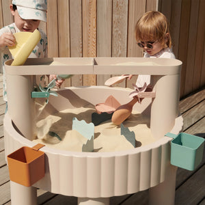 Toddlers are playing with the Liewood sepp table in summer.