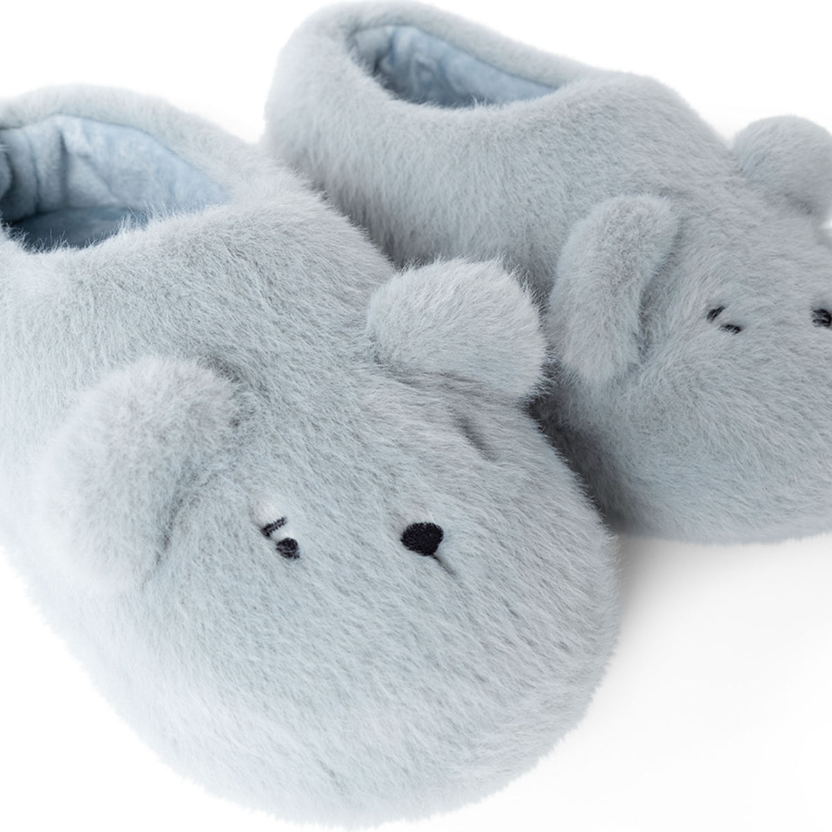 A close-up view of the dove blue Liewood Aviaja bear slippers, focusing on the cute embroidered bear eyes, snout, and soft ears.