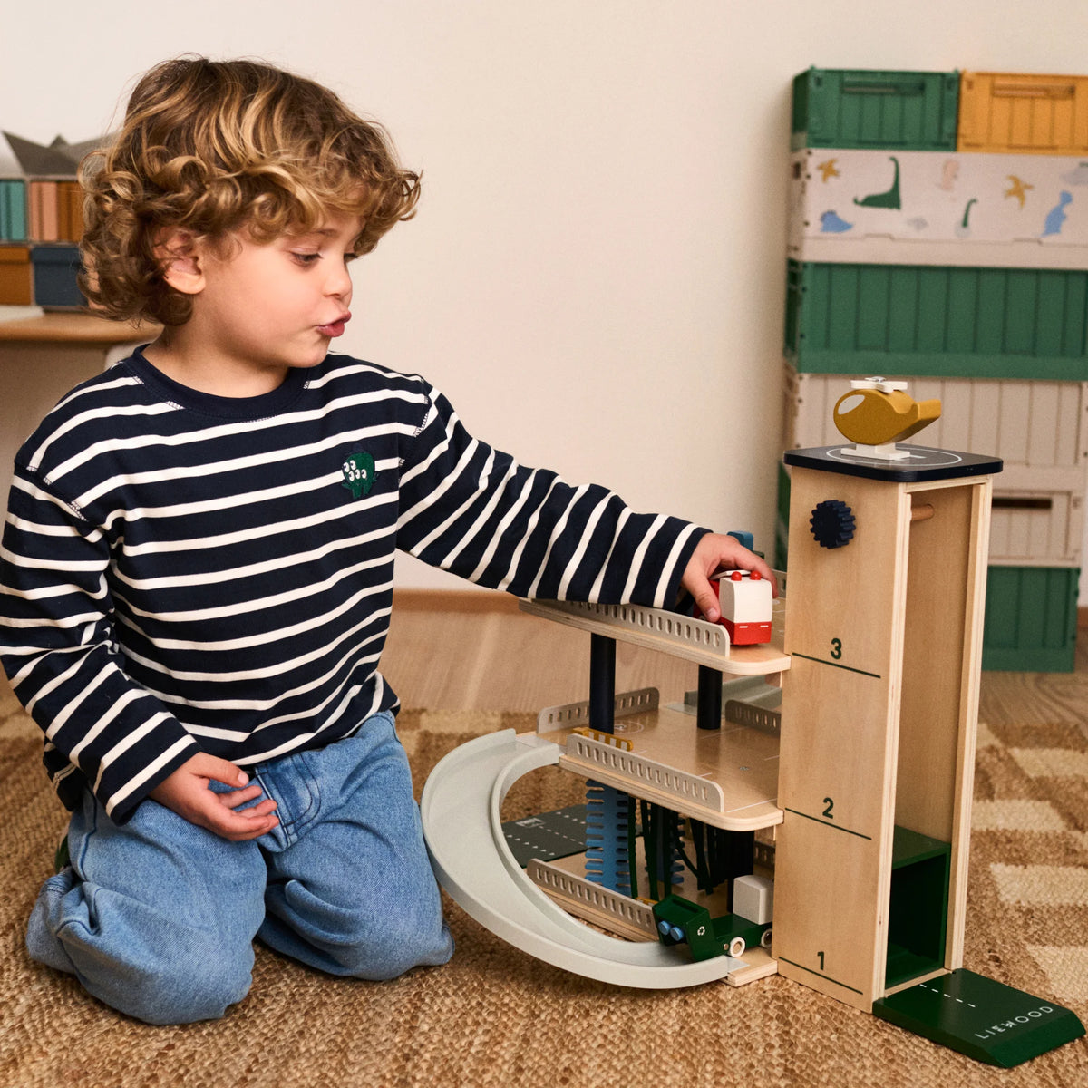 Boy exploring rotating elevator and play zones on Liewood Jordy parking tower