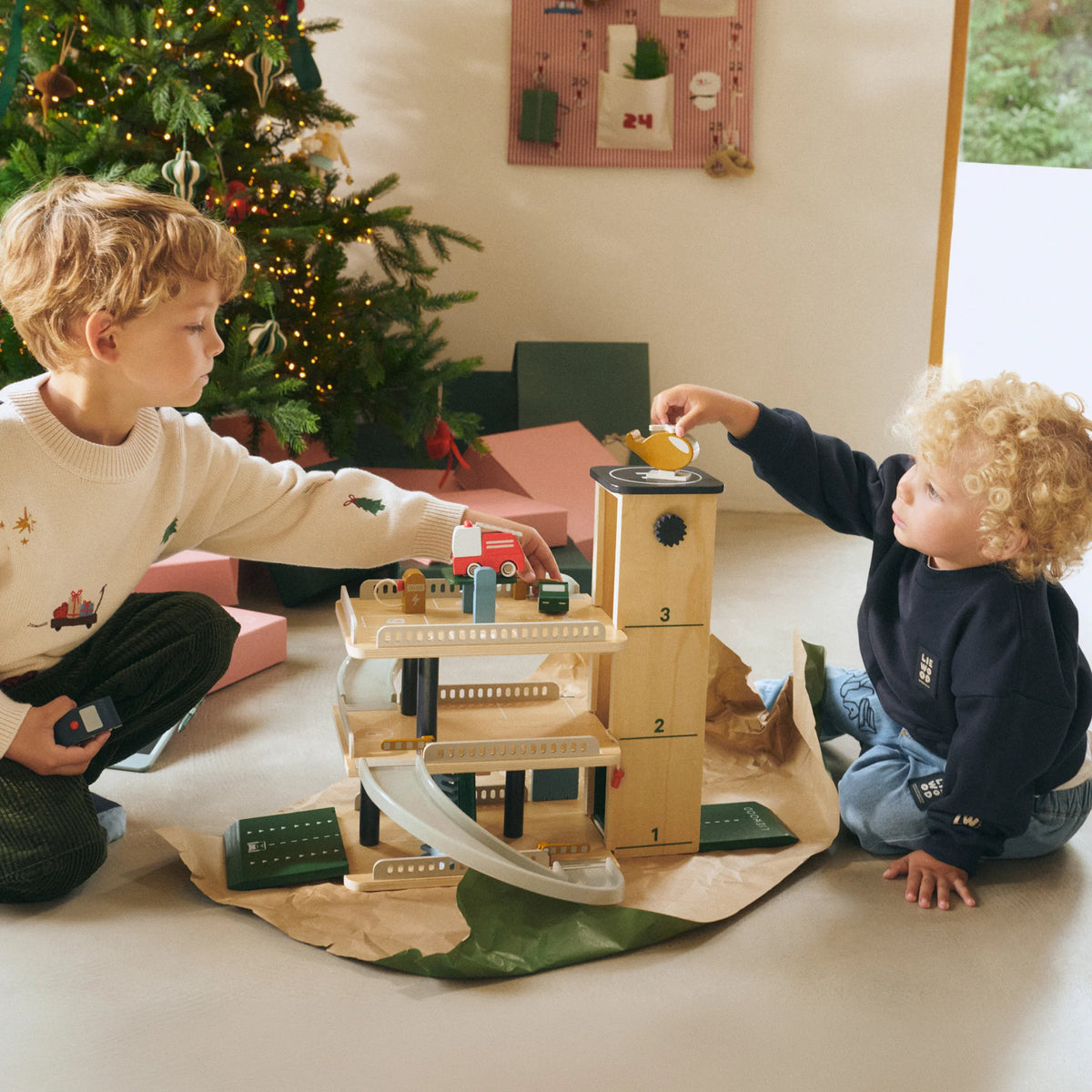 Young children playing with Liewood Jordy wooden parking tower indoors