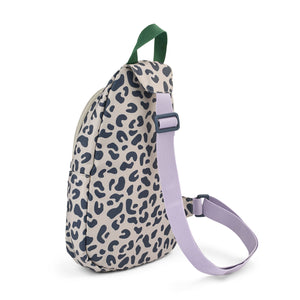 Back angle view of a Liewood leopard print one shoulder backpack showing its adjustable lilac purple crossbody strap and green handle
