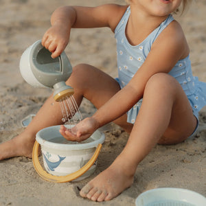 Little Dutch watering can pouring water on sand – outdoor play scene