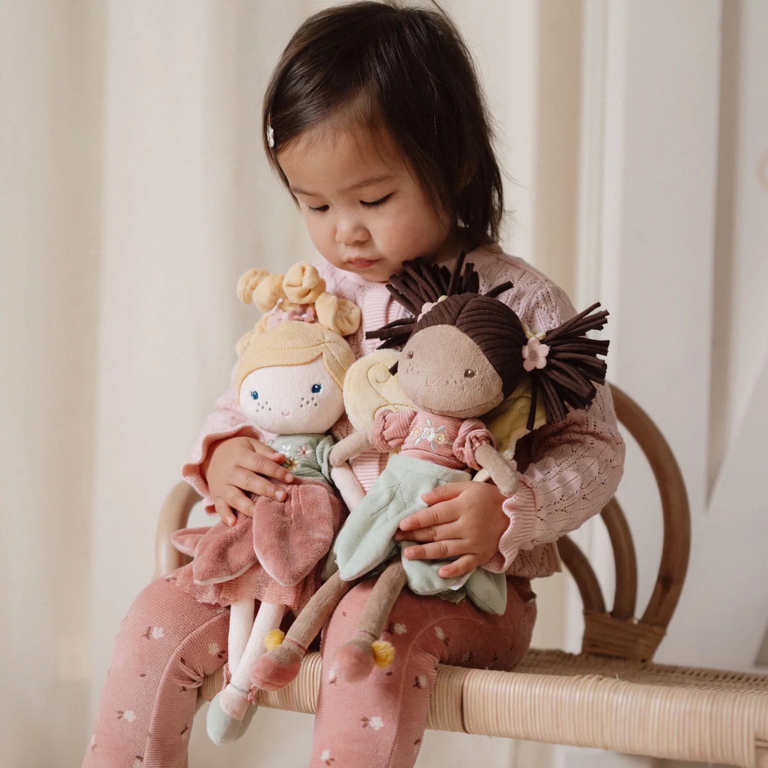 A toddler is playing with the cuddle doll evi fairy garden.