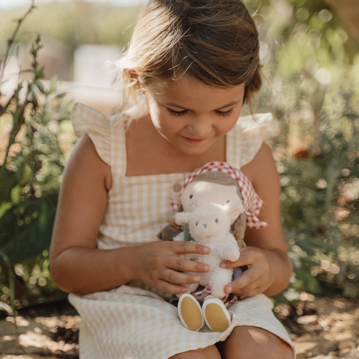 A girl is playing outdoor with the cuddle doll farmer rosa.