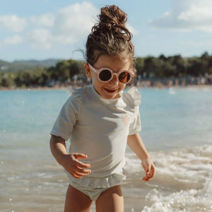 Child wearing Little Dutch Round Sunglasses in Ocean Dreams Pink outdoors.