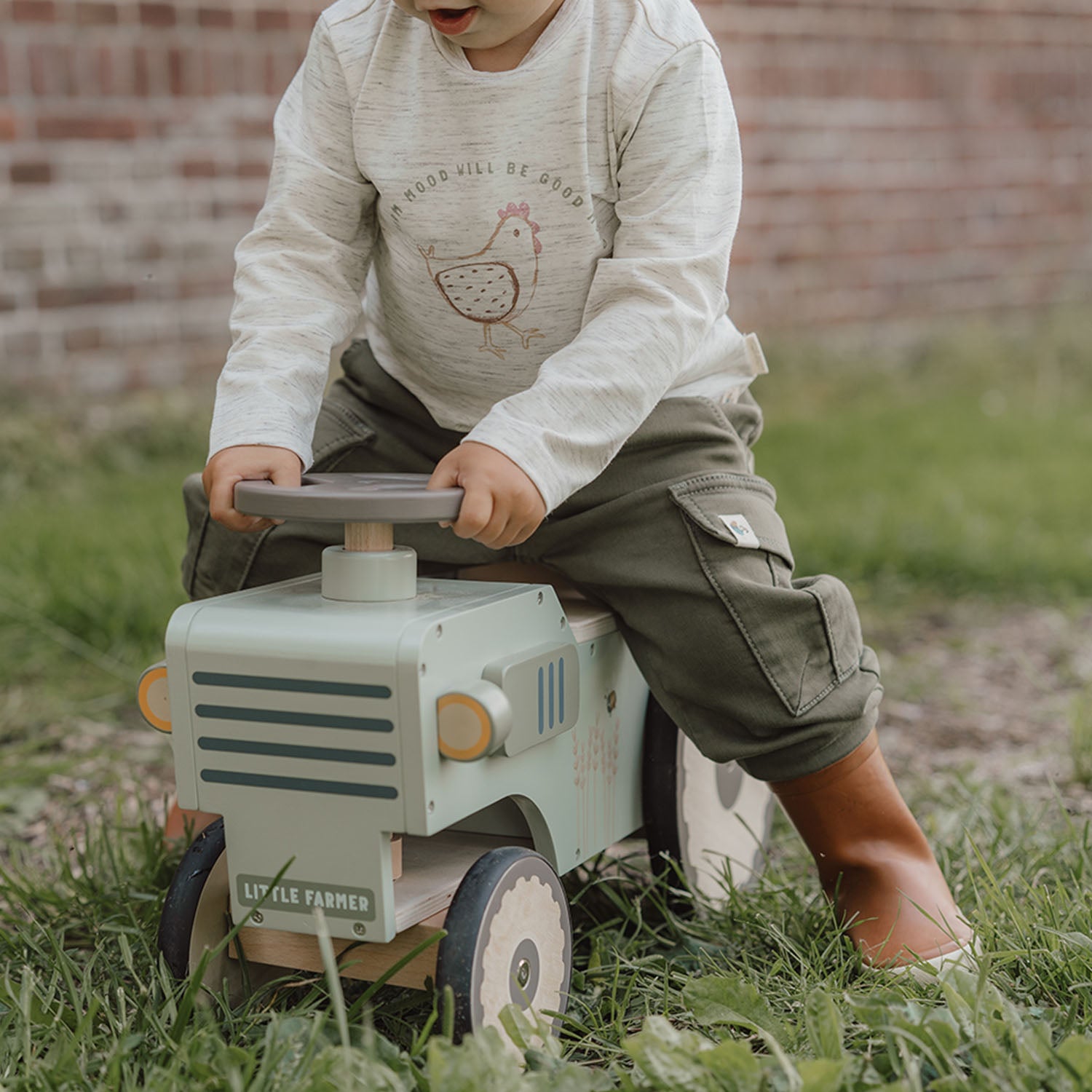 Toddler playing on Little Dutch wooden tractor toy.