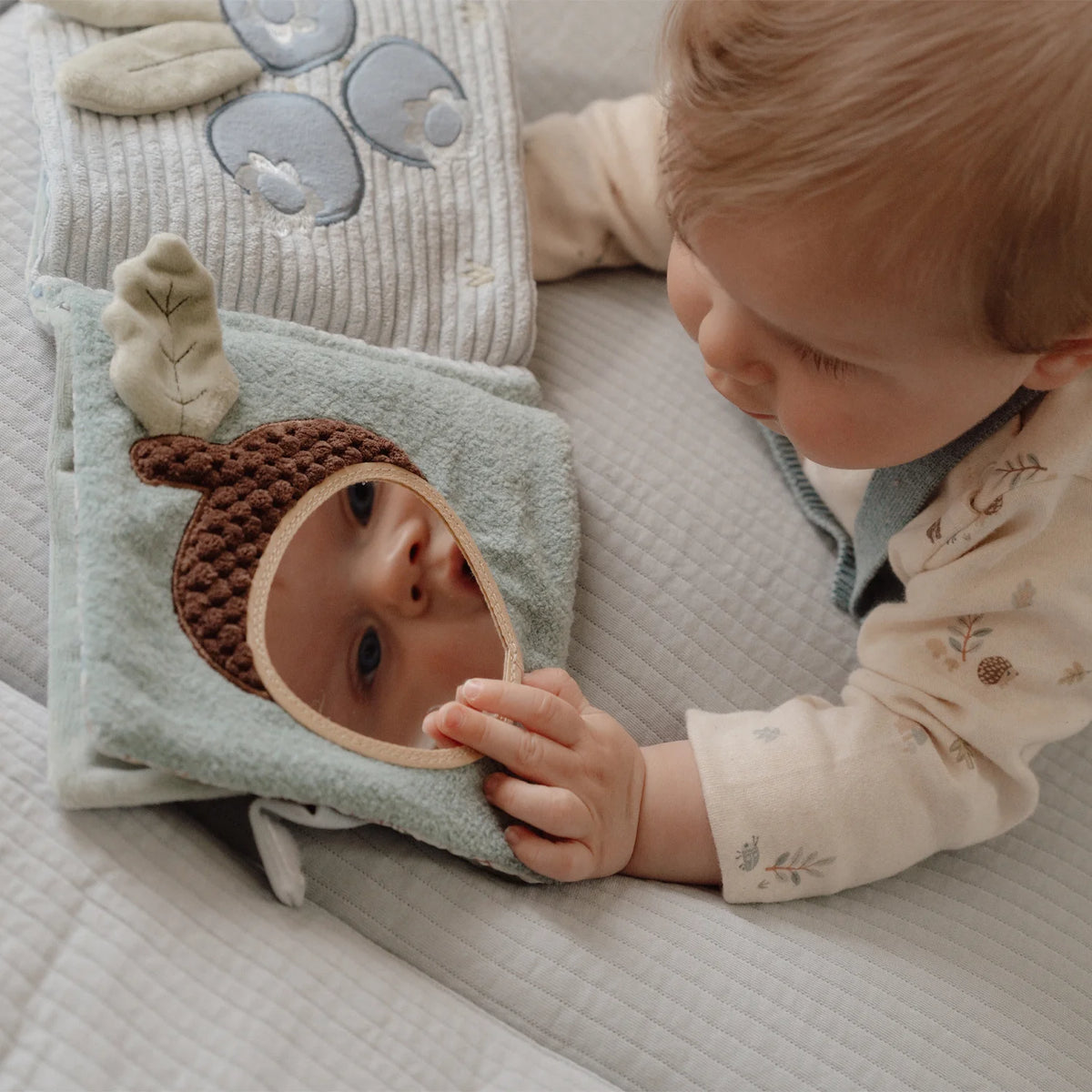 Baby is playing with the mirror - Little Dutch soft activity book.