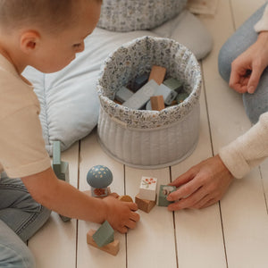 A boy and a mother are storing the wooden blocks.