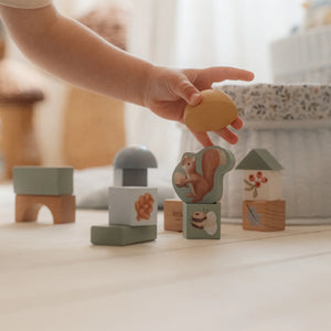 A baby building a forest out of colorful blocks.