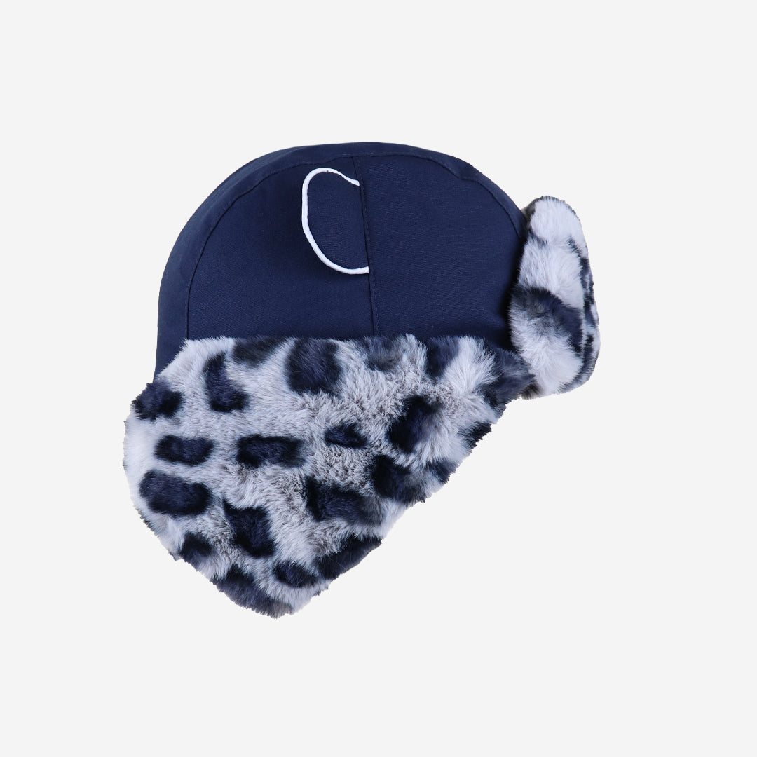 Navy blue winter hat with white fur trim on a light gray background
