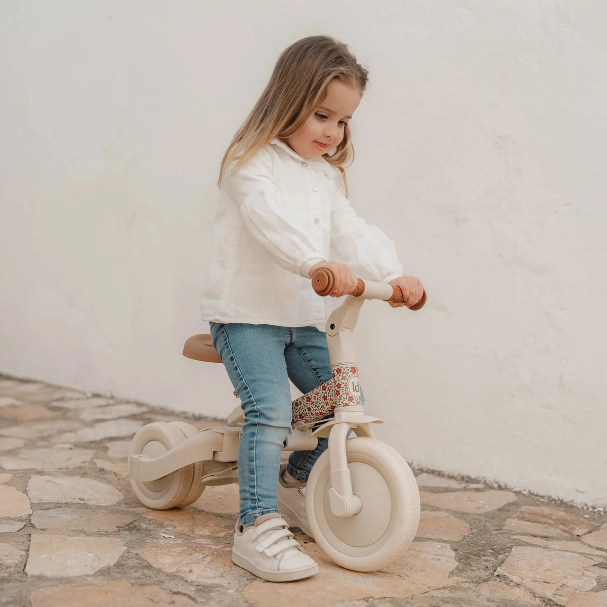 Child holding natural wood finish Little Dutch tricycle ready to ride