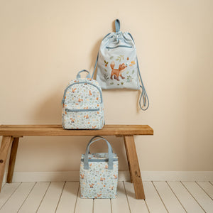 A matching set of Little Dutch Forest Friends gear, including a backpack and cooler bag, sitting on a wooden bench.