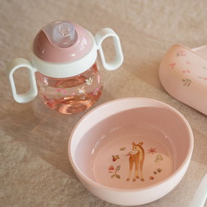 Little Dutch 200ml antileak spout cup in the pink Fairy Garden design sitting on a table next to a matching pink children's bowl.