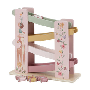 A pink fairy garden wooden ramp racer toy with a deer illustration on the side, showing four tiers of pastel-colored tracks and four small matching toy cars lined up at the base.