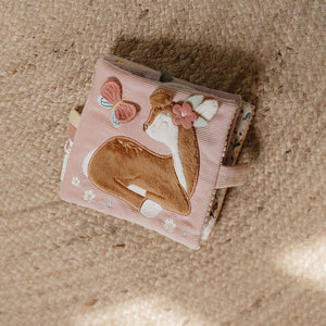 Small pink book with deer illustration on a textured surface
