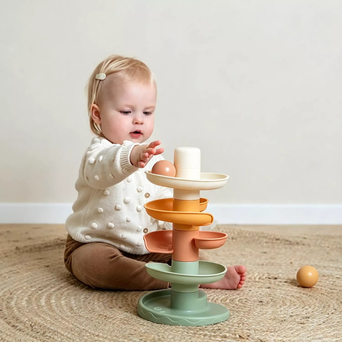 A baby is playing with the little dutch spiral tower.