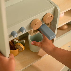 Close-up of a child's hands attaching the wooden portafilter to the toy espresso machine.