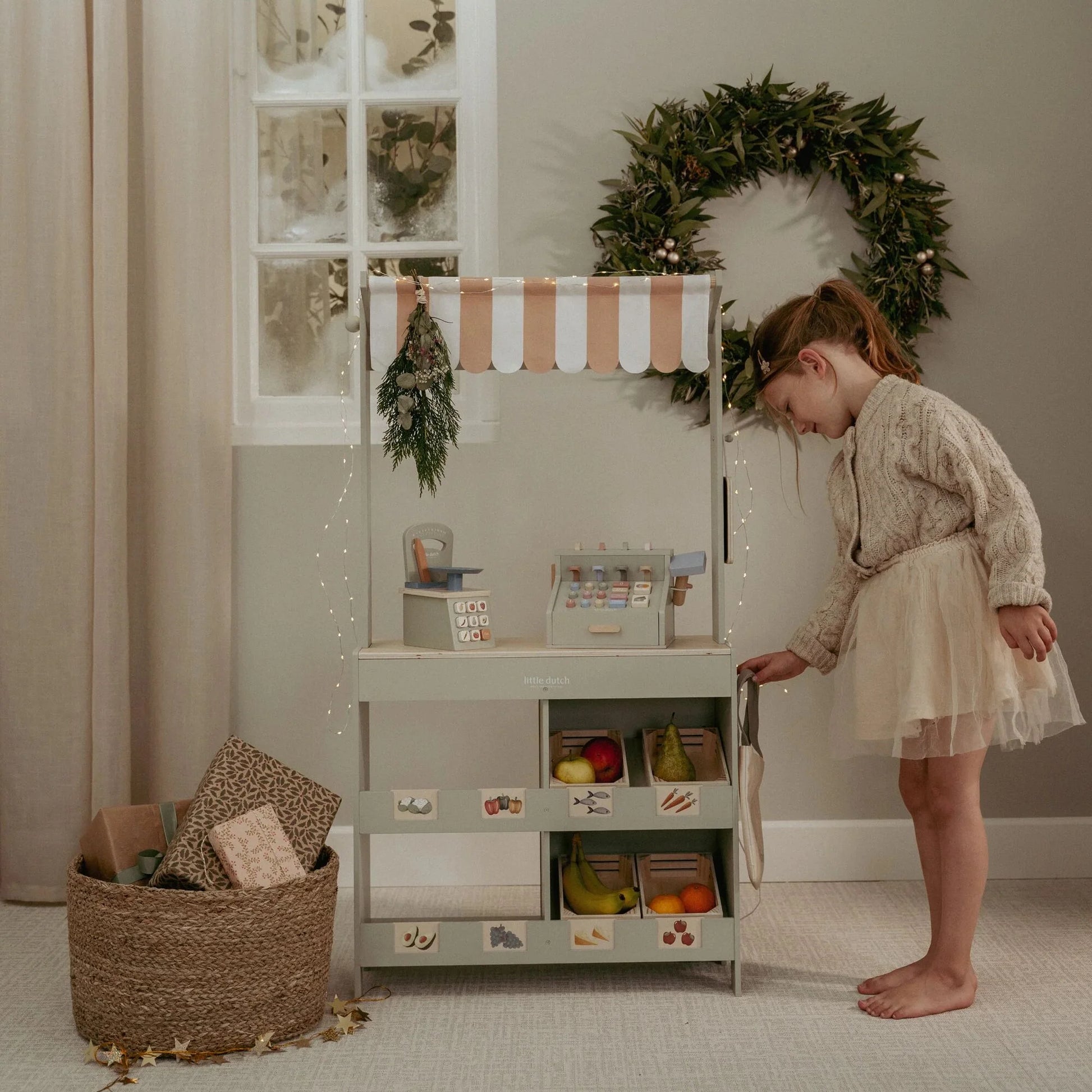 Child playing shop with Little Dutch wooden market stall during Christmas.
