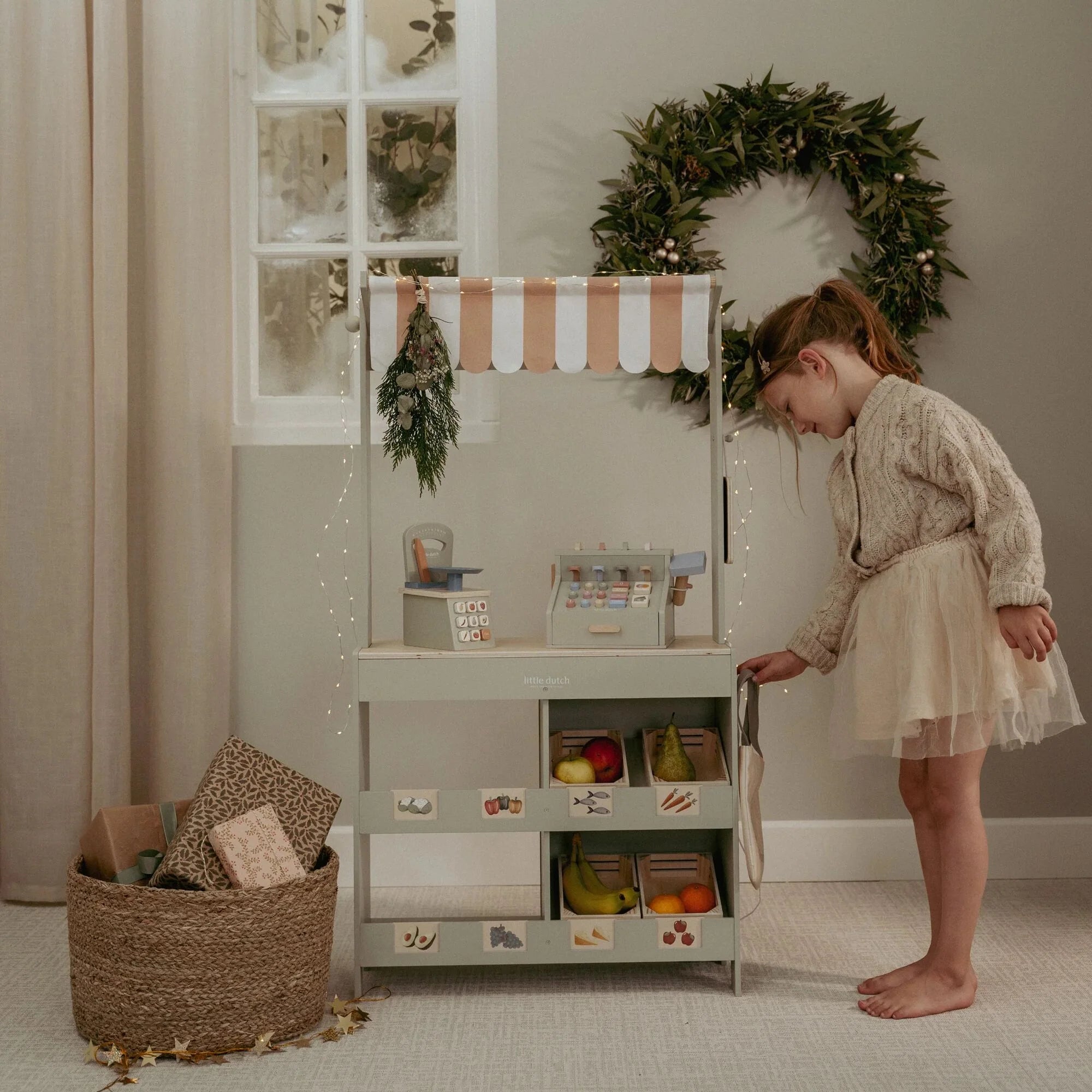 Child playing shop with Little Dutch wooden market stall during Christmas.