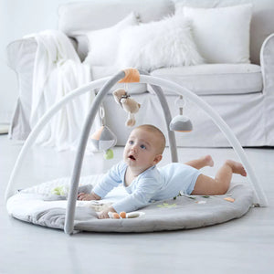 The baby is playing with the Luxury Musical Baby Playmat, which comes with a soft cushioned mat.