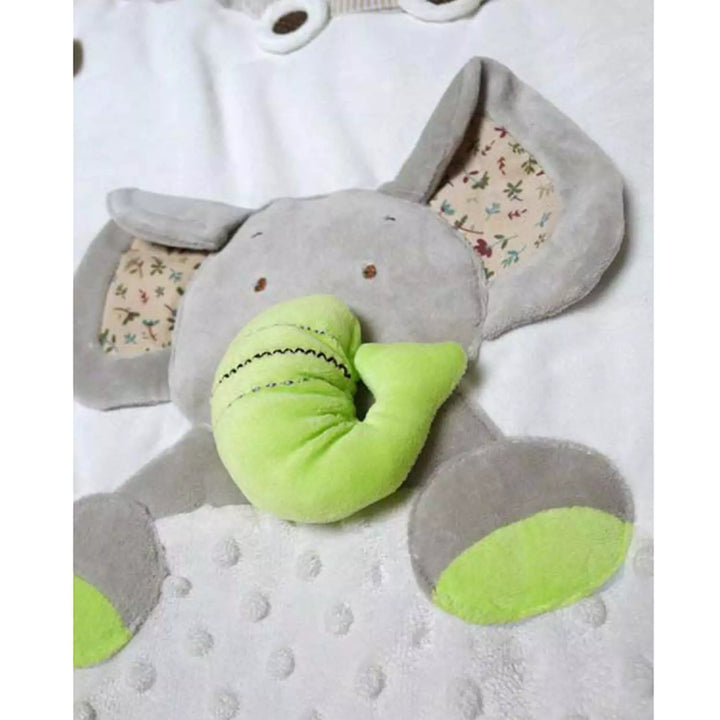 A brightly colored baby play gym with a green stuffed elephant with a trunk hanging above a white play mat
