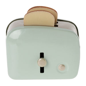 A miniature metal toaster in green color with two slices of bread sticking out from the top, designed for pretend play.