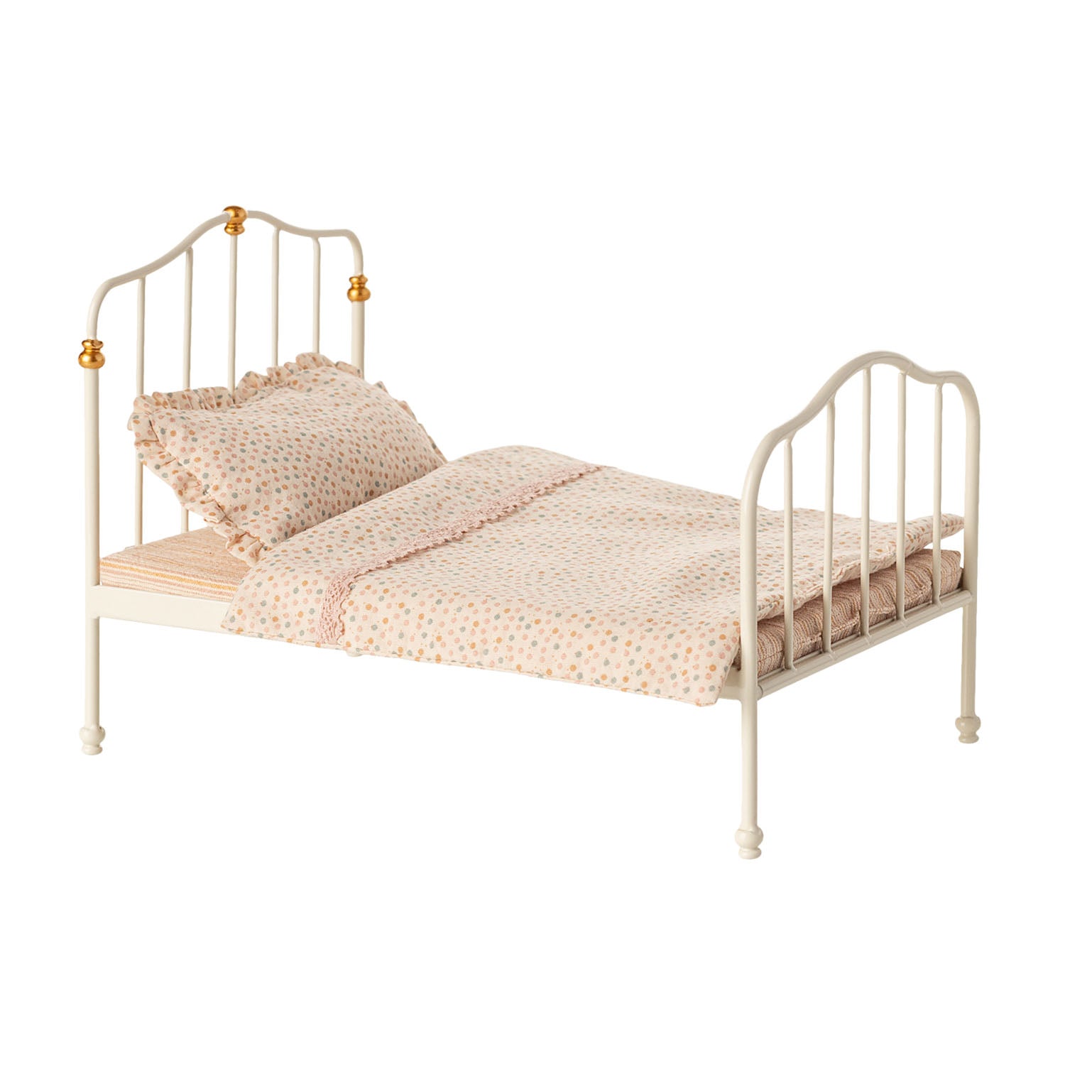 Miniature bed with colorful patterned mattress, pillow, and blanket.